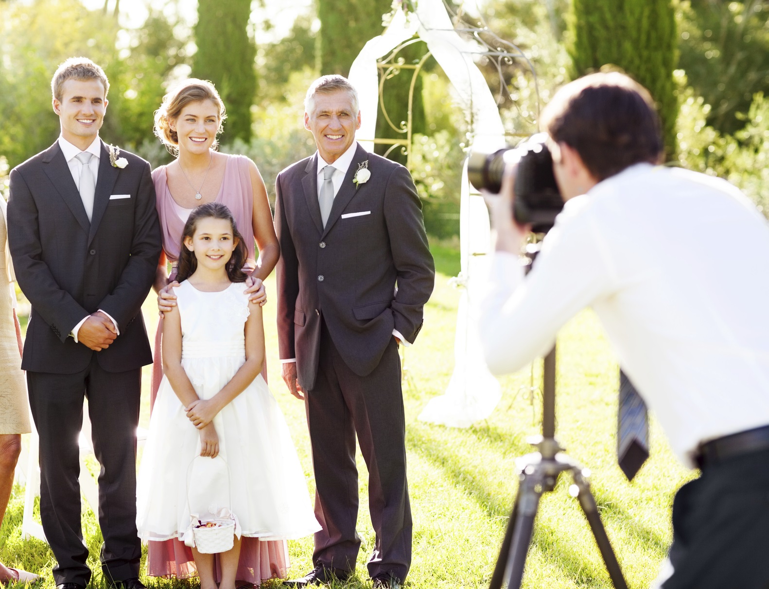 Family Posing While Man Photographing Them At Outdoor Wedding